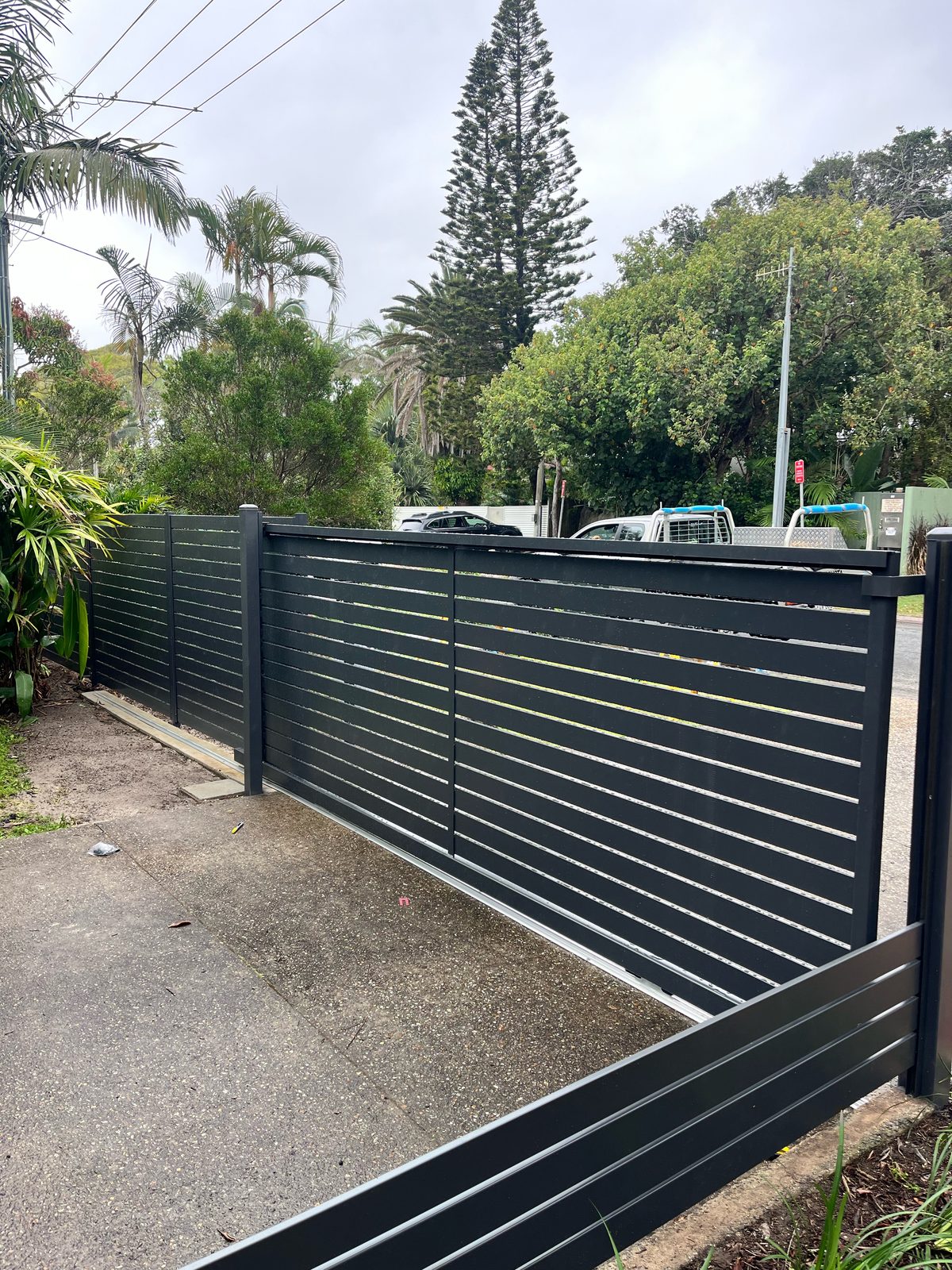 Charcoal aluminium slat sliding driveway gate with matching slat fence