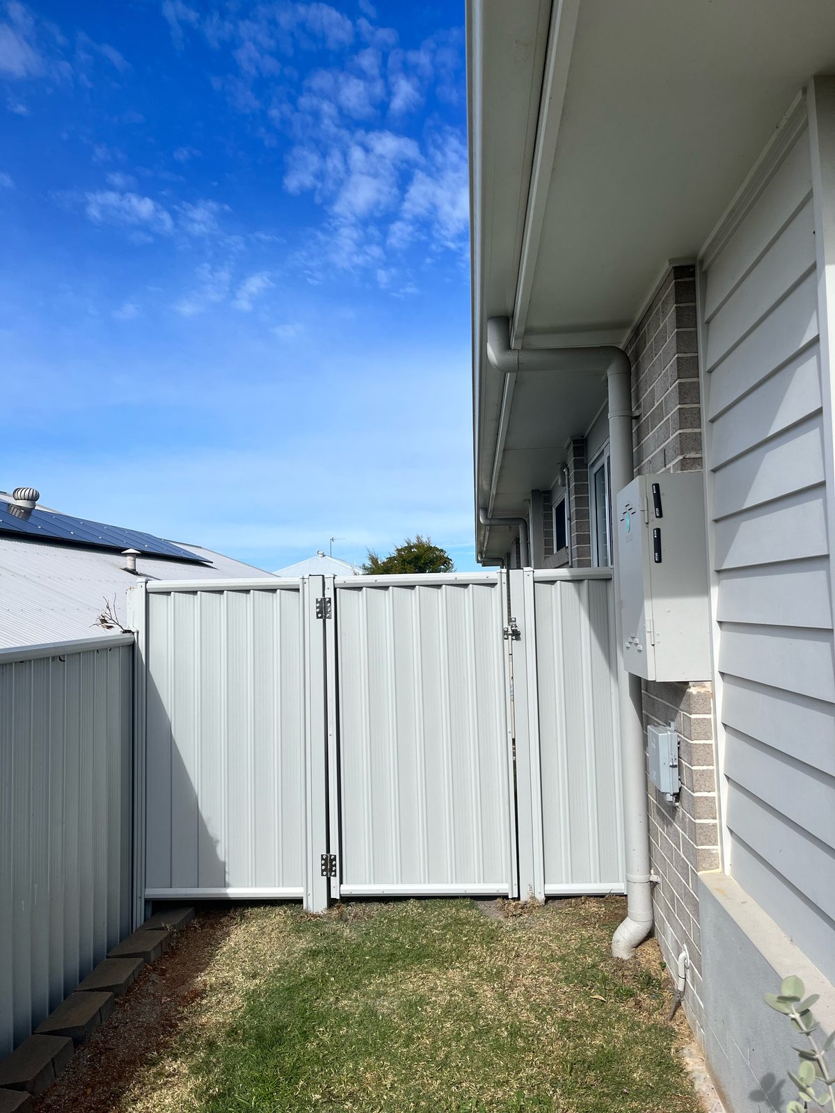 Pale Colorbond side fence with a matching pedestrian gate
