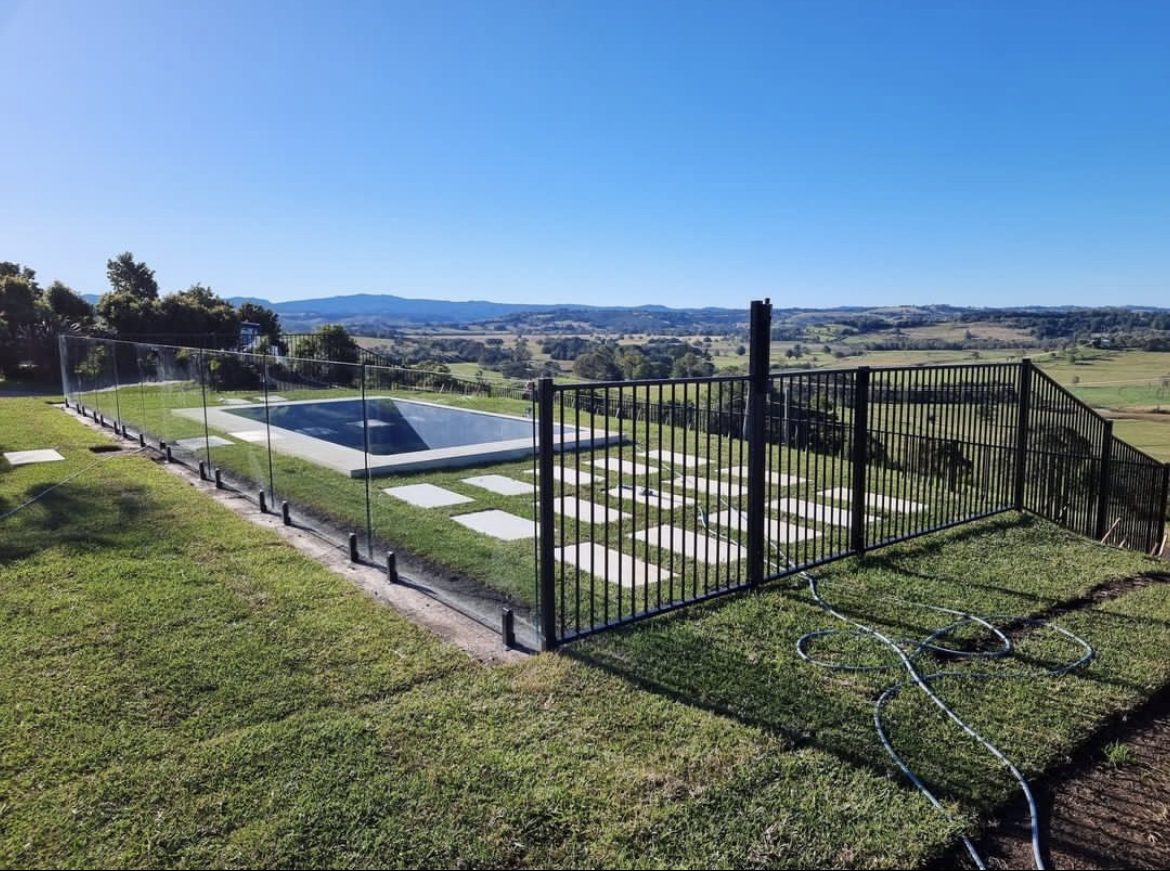 Frameless glass and black tubular aluminium pool fence with rural hinterland views