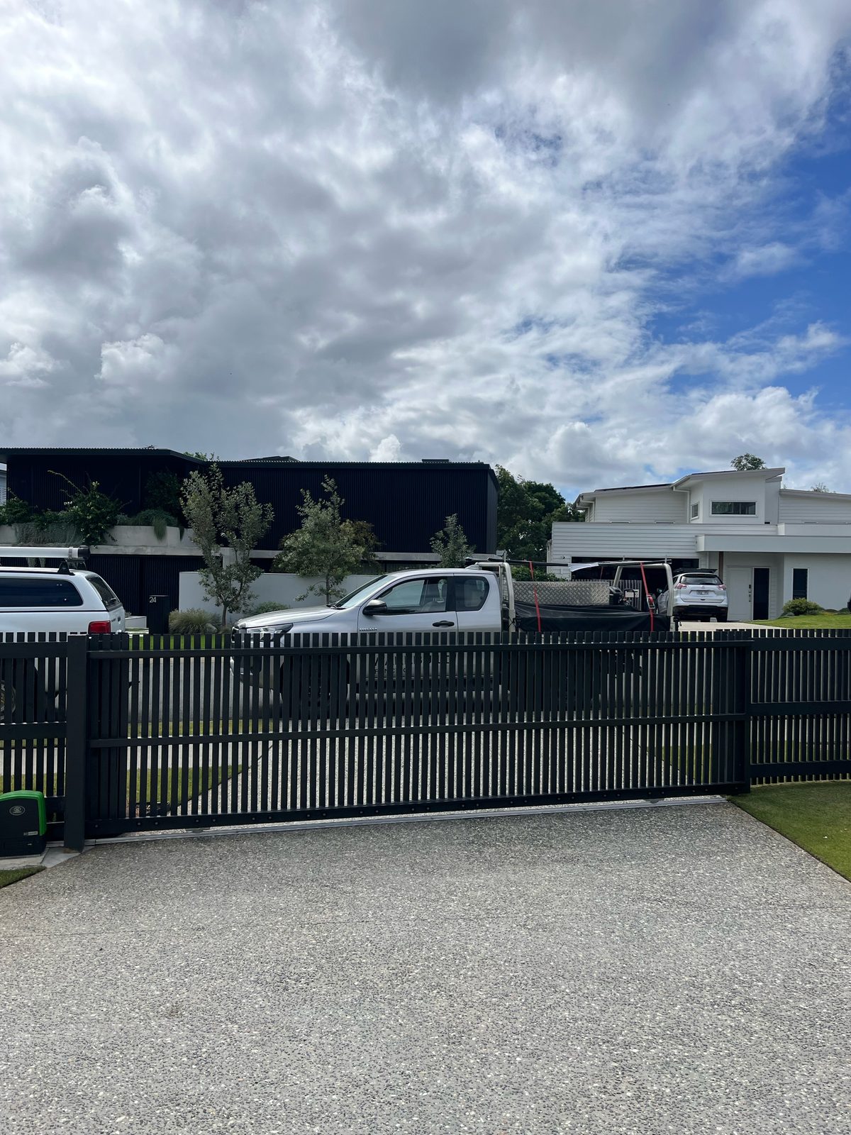 Black vertical slat sliding driveway gate with matching fence